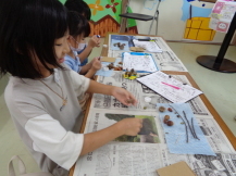 どんぐりや木の棒を使って工作をしている子どもたちの写真