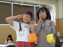 折り紙で作ったバッグを持ってピースサインをしている2名の女の子の写真