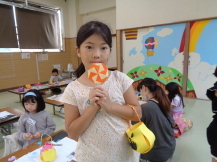 折り紙で作ったペロペロキャンディーやバッグを持っている女の子の写真