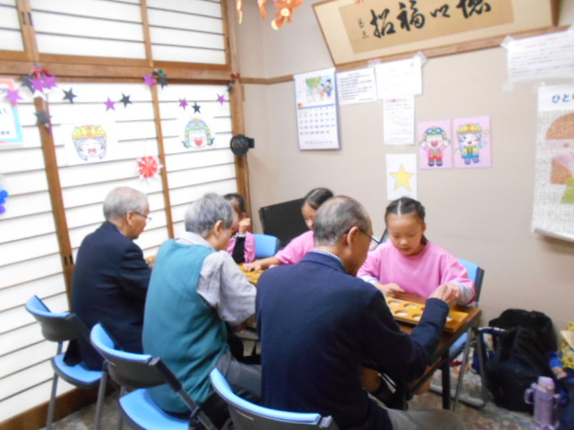 シニアの方と子どもたちがマンカラをしている写真
