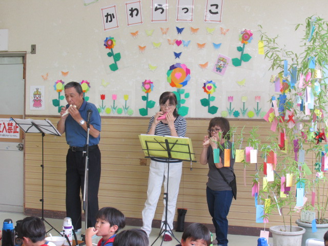 子どもの前に立ちオカリナの演奏をする成人男性1名と成人女性2名