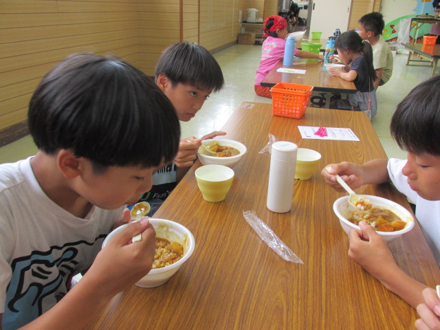 座卓でカレーを食べる小学校高学年3人の写真