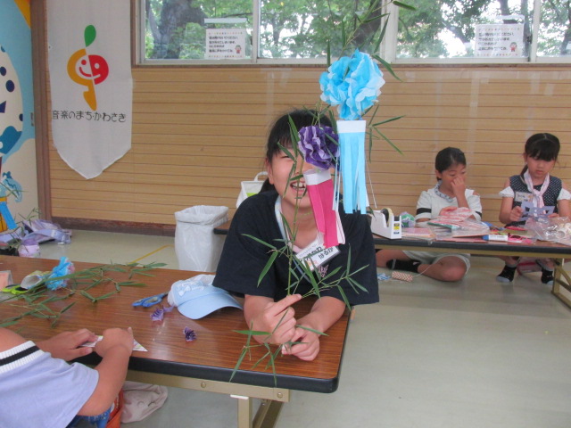 自分で製作した七夕飾りを笹につけ工作のできを喜ぶ女の子の写真