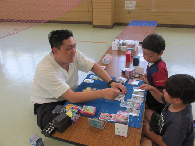 講師の方からポケモンカードのやり方を習う小学生男子2名の写真