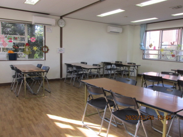 4脚の椅子がセットになった長机が6台置かれている遊戯室の写真