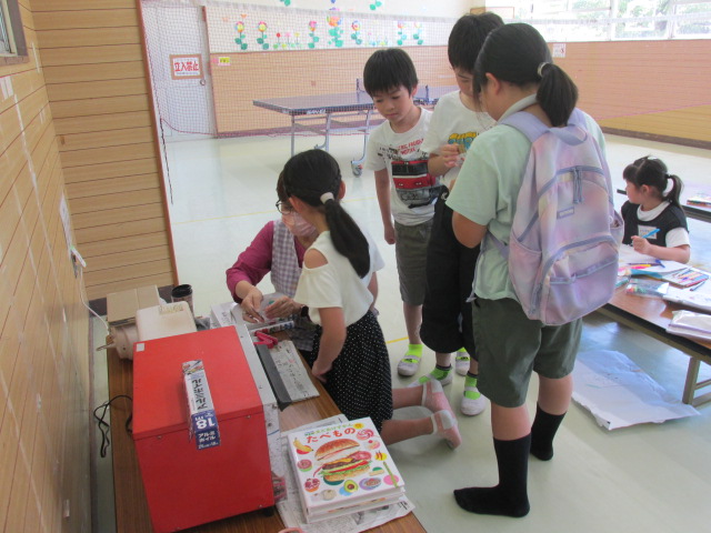 プラ板をオーブンで加熱し、変化する様子を見る小学生たちの写真