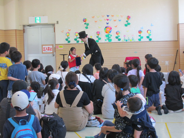 マジシャンのお手伝いをする小学生女児の写真