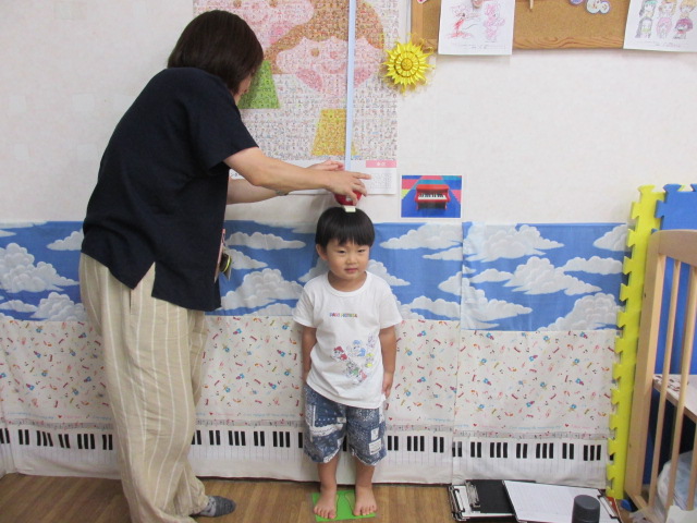 立ち姿で身長を測っている幼児の写真