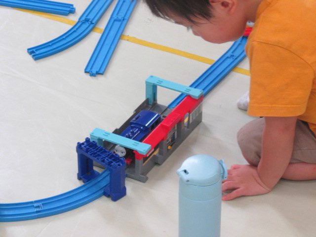 男の子がプラレールの電車を見つめている写真
