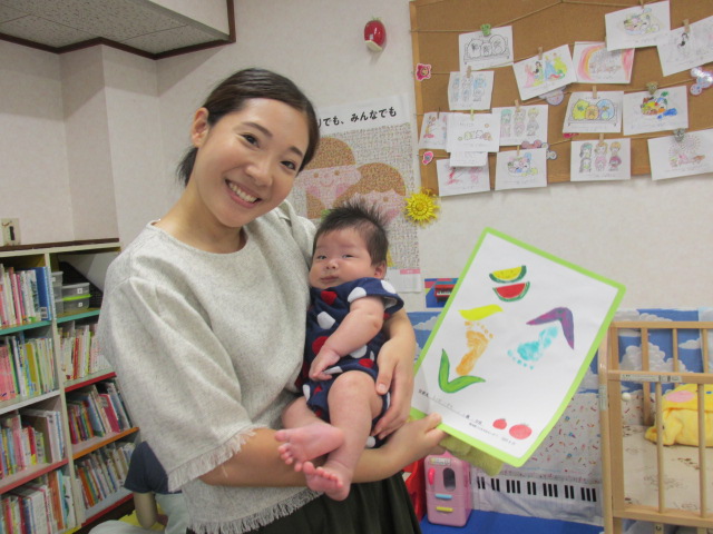 母と乳児が完成した足形アートと映っている写真