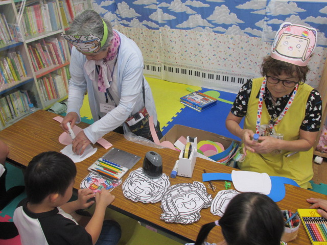 おめんづくり工作で色塗りをしている子どもの写真