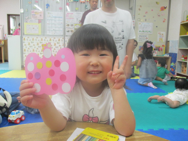 シールを貼ったピンクのかぼちゃを持ってピースする女の子の写真