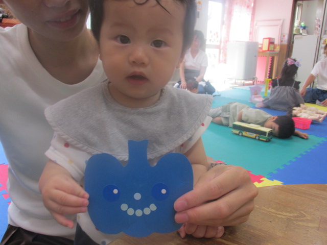 シールで顔を作った青いカボチャを持つ親子の写真