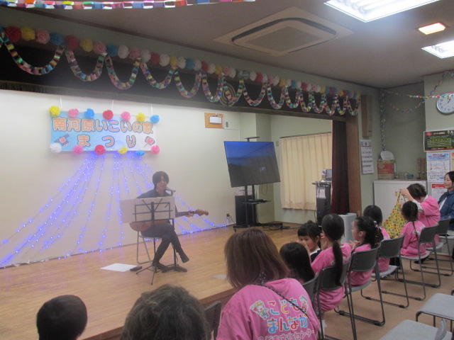 ステージで高校生がギターの弾き語りをしている写真