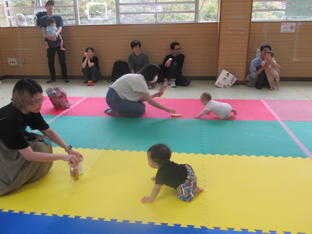 マットの上でハイハイ競争をする赤ちゃんたちの写真