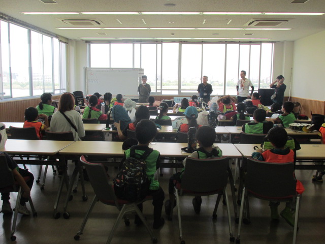 教室風の部屋で子どもたちがスタッフの方の話を聞いている写真