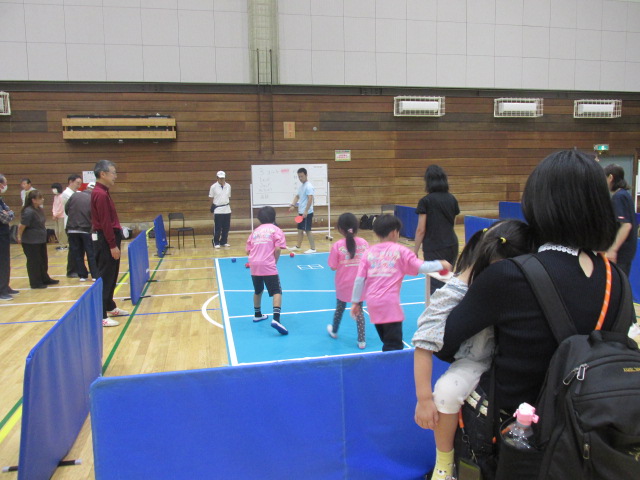 女の子をだっこしながらボッチャの試合を見守る保護者の背中