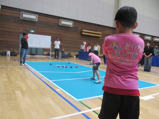 チームメイトの投球を見守る男の子の背中