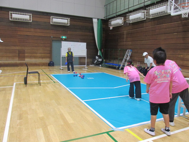 3人の子どもたちがボッチャの試合をしている写真