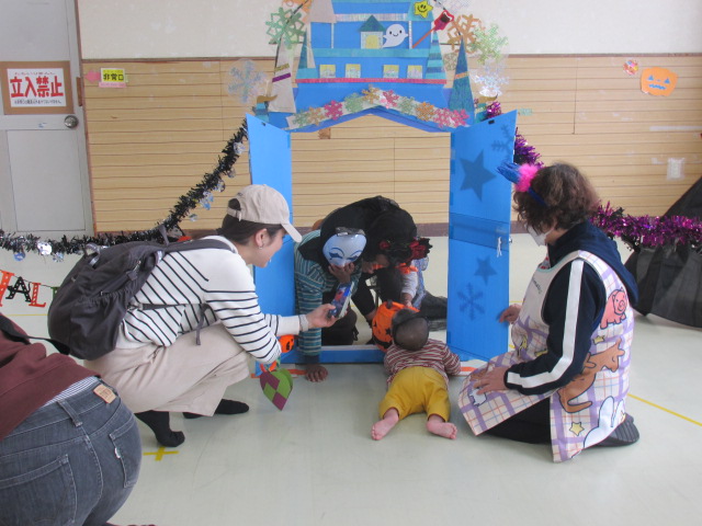 ハロウィンの館をノックしてキャンディーをもらっている乳児の写真