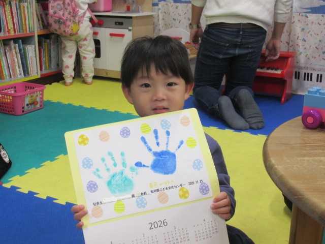 手形のカレンダーを持った男の子の写真