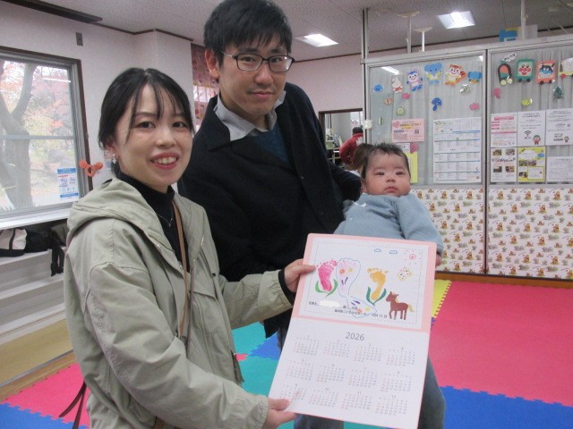 ご両親が赤ちゃんと足形のカレンダーを見せている写真