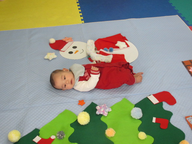 雪だるまと並んで寝転んでいる乳児の写真