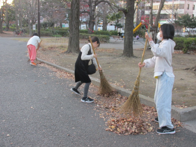 園路を竹ぼうきで掃いている子どもたちの写真