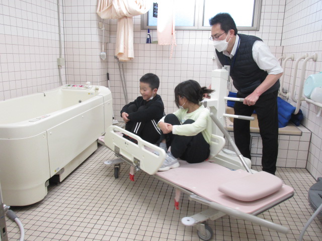 高齢者の入浴を介助する機会に子どもがのせてもらっている写真