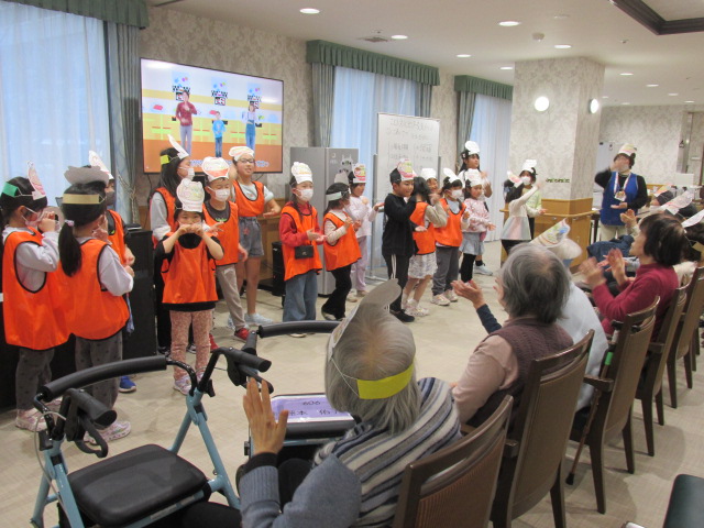 子どもたちが高齢者とラーメン体操をしている写真