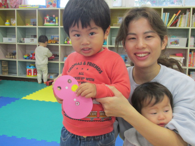 ピンクの雪だるまにシールを貼った作品と親子で写っている写真