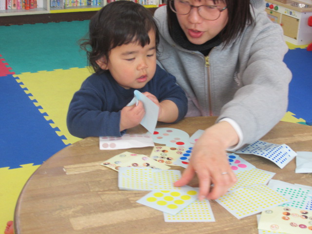 母とシールを選んでいる幼児の写真