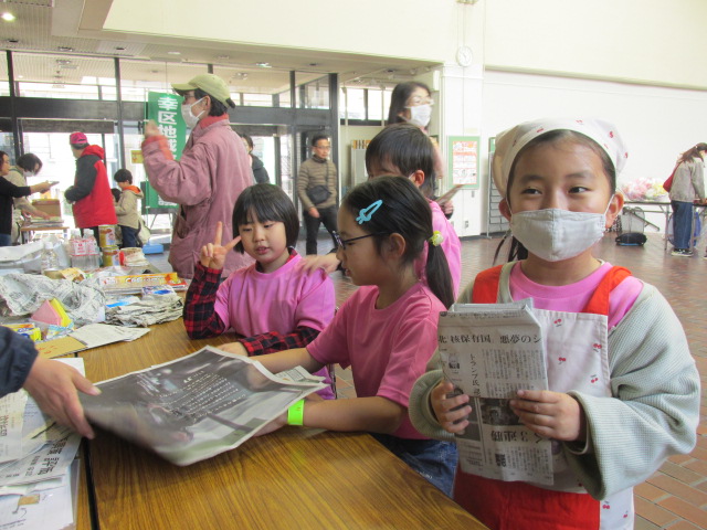 空き時間に防災ブースで新聞紙スリッパを作っている子どもたちの写真