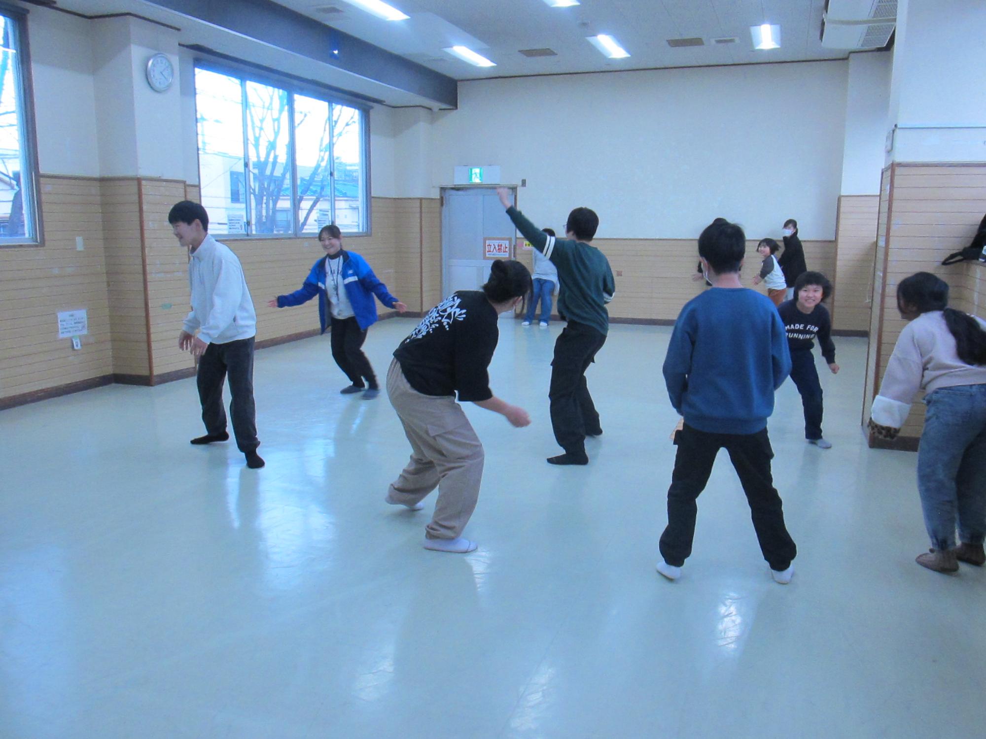 反対側の壁に向かって走る子をオニが中央で捕まえようとしている写真