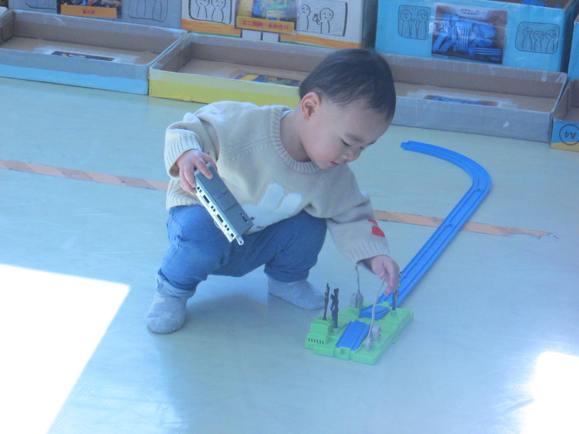 踏切のパーツで動きを楽しんでいる幼児の写真