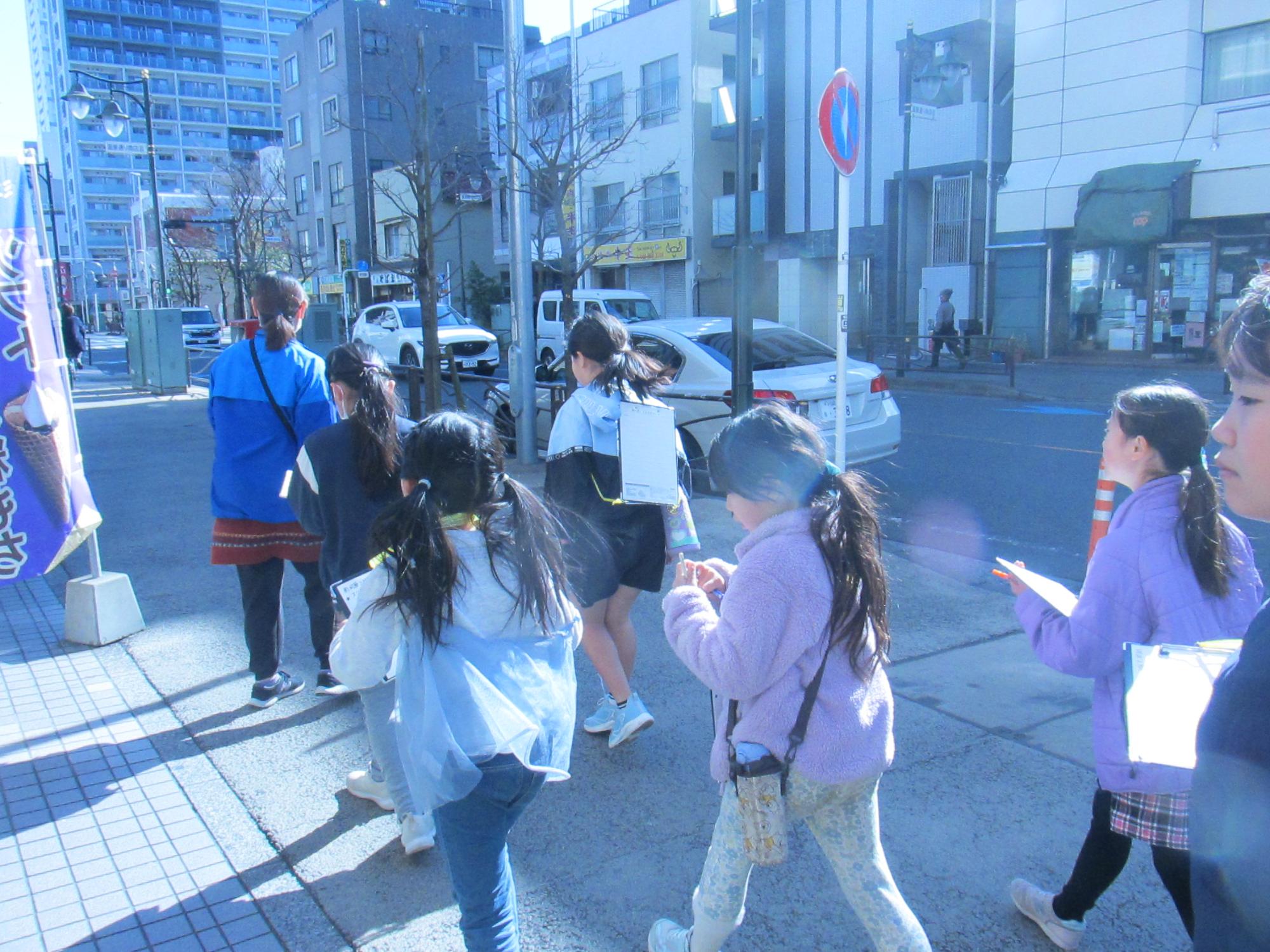 車の多い道路の歩道を歩いている写真