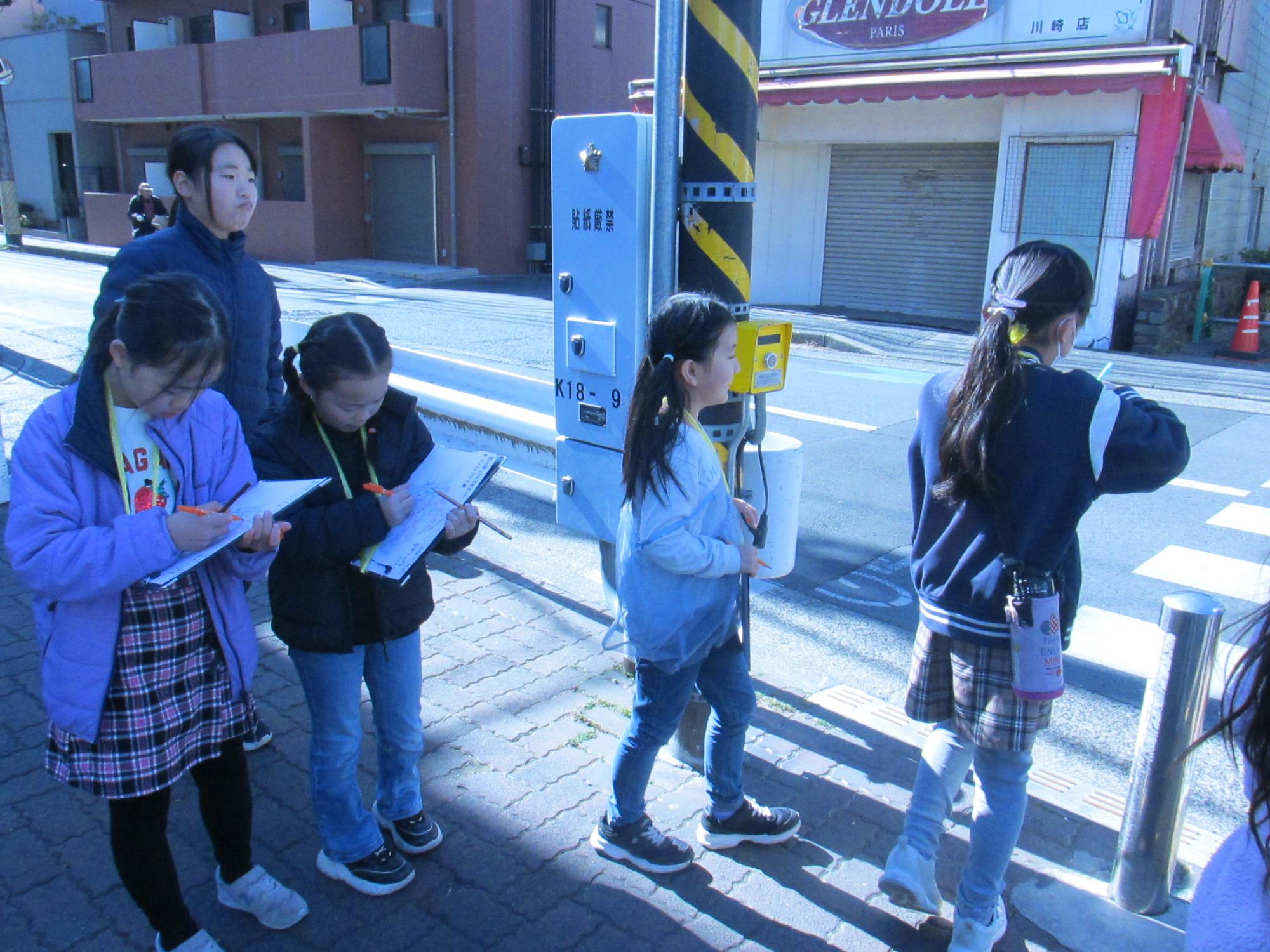 手押し信号の横断歩道の場所をメモしている写真