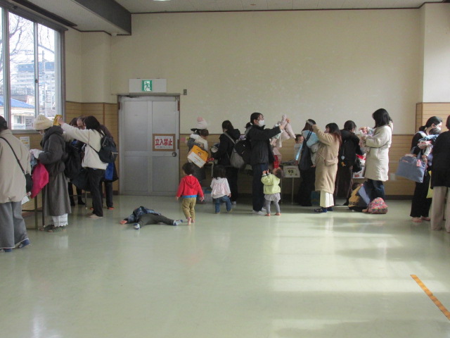 リユース品からお母さんたちが子どもに合う衣類を選んでいる写真