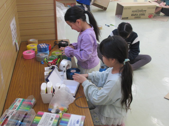 いろいろな材料を使ってテーブルで工作している女の子たちの写真