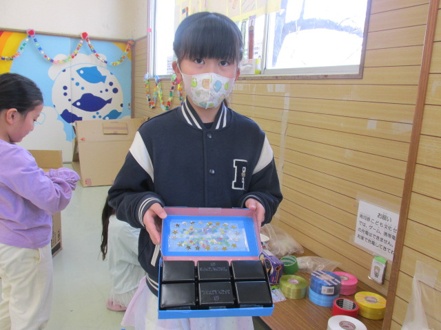 空き箱にビーズ等で飾りをつけた作品を持っている女の子の写真