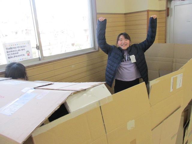 ダンボールハウスでバンザイしている子どもの写真