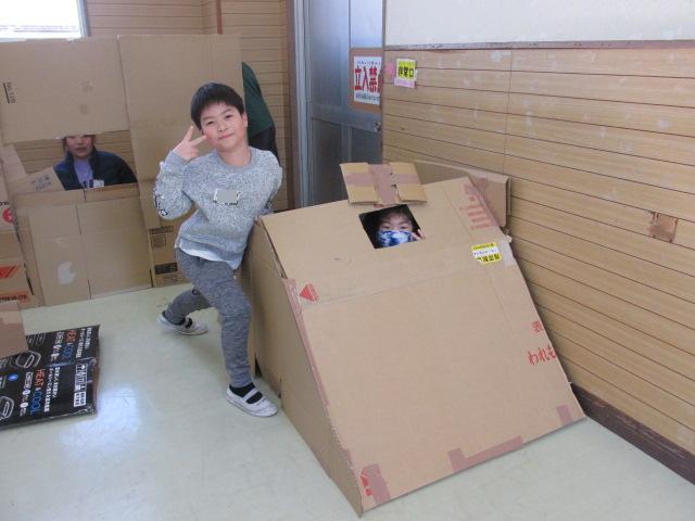 テントのようなダンボールハウスで遊んでいる子どもの写真