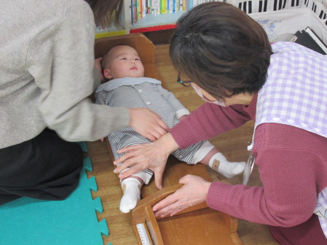 寝転がって身長を測っている幼児の写真