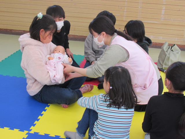 赤ちゃんのお人形でだっこを体験している子どもの写真