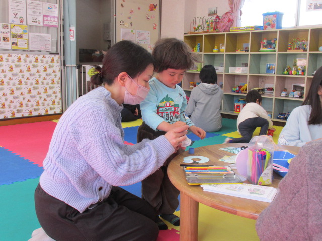 シール貼りをしている幼児親子の写真