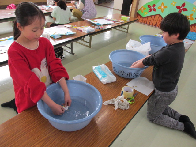 水にシールをつけて紙を溶かしている写真