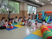 大きな滑り台付きのバルーン遊具と大勢の子供たちと母親を全体的に撮影した写真