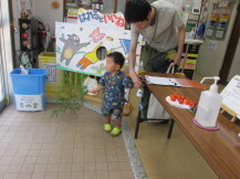 お父さんと手をつないだ小さな男の子がもらった笹を片手に玄関から帰ろうとしている写真