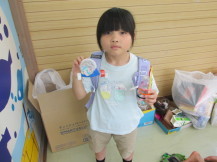 リュック姿の女の子が両手に手作りのおもちゃを持っている写真