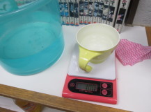 はかりの上に水がいっれられたコップが置かれ重さをはかっている写真